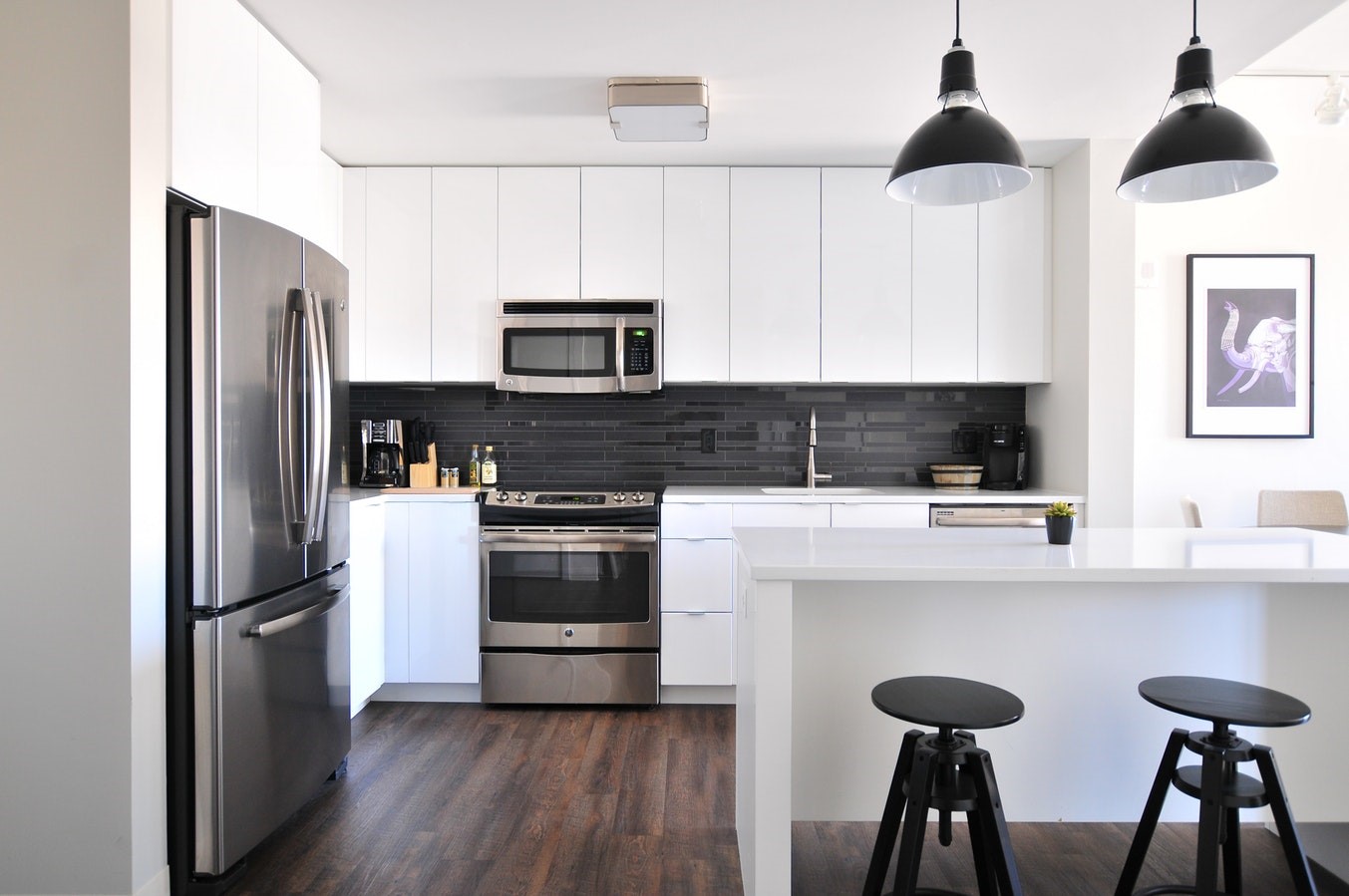 Kitchen with white cupboards, dark hardwood floor and stainless steel applicances