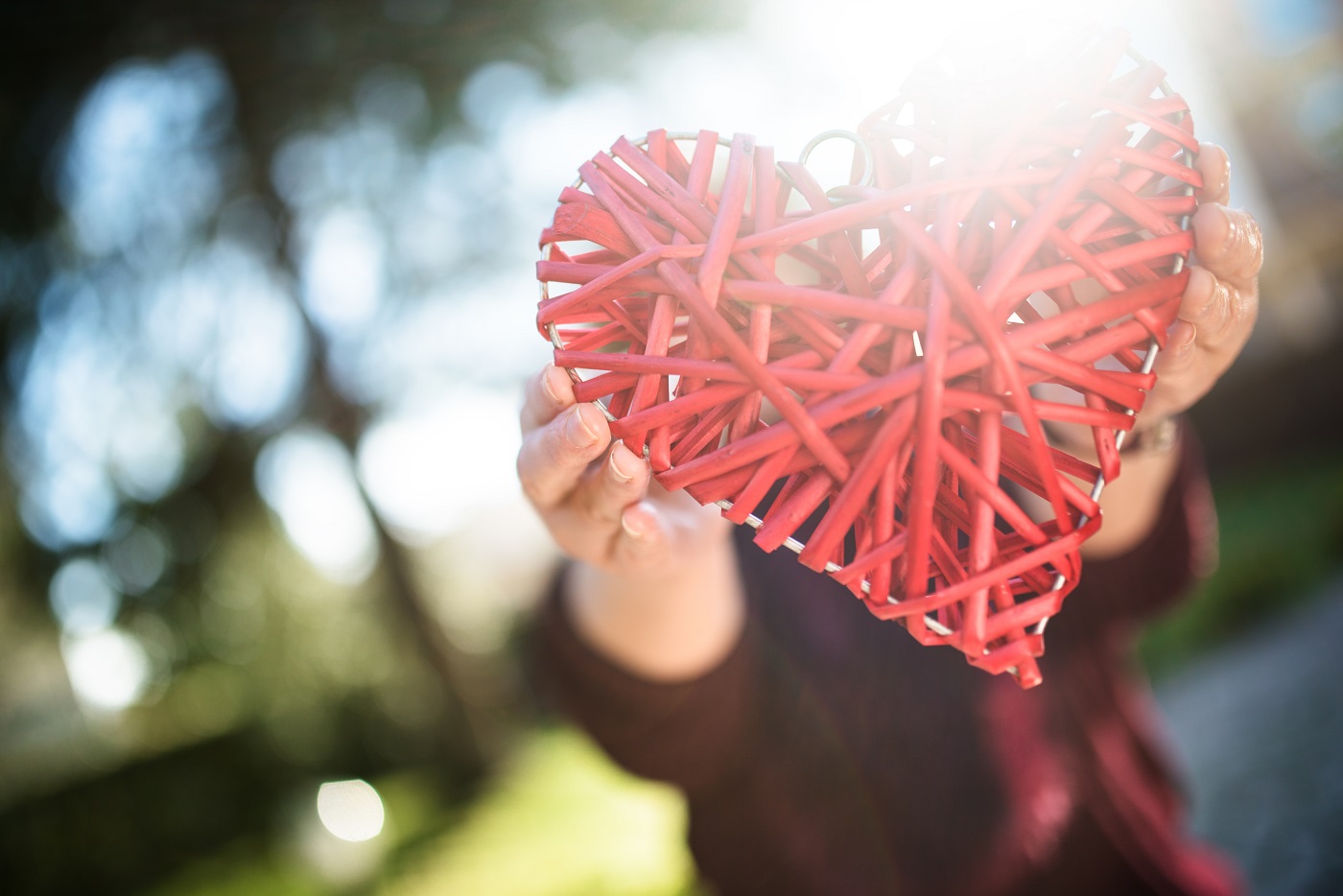 person holding an wooden heart with sun backlight