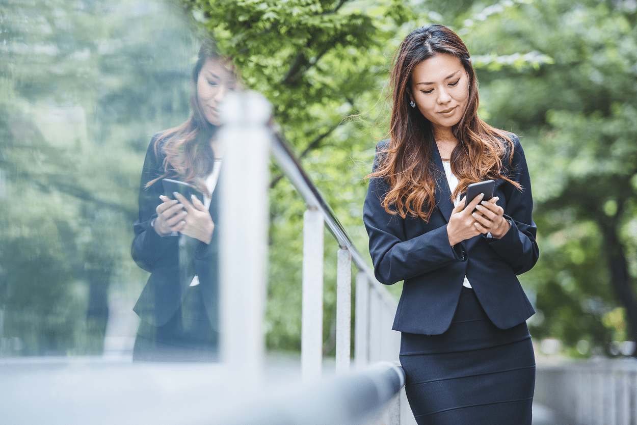 young woman using smart phone outside with greenery