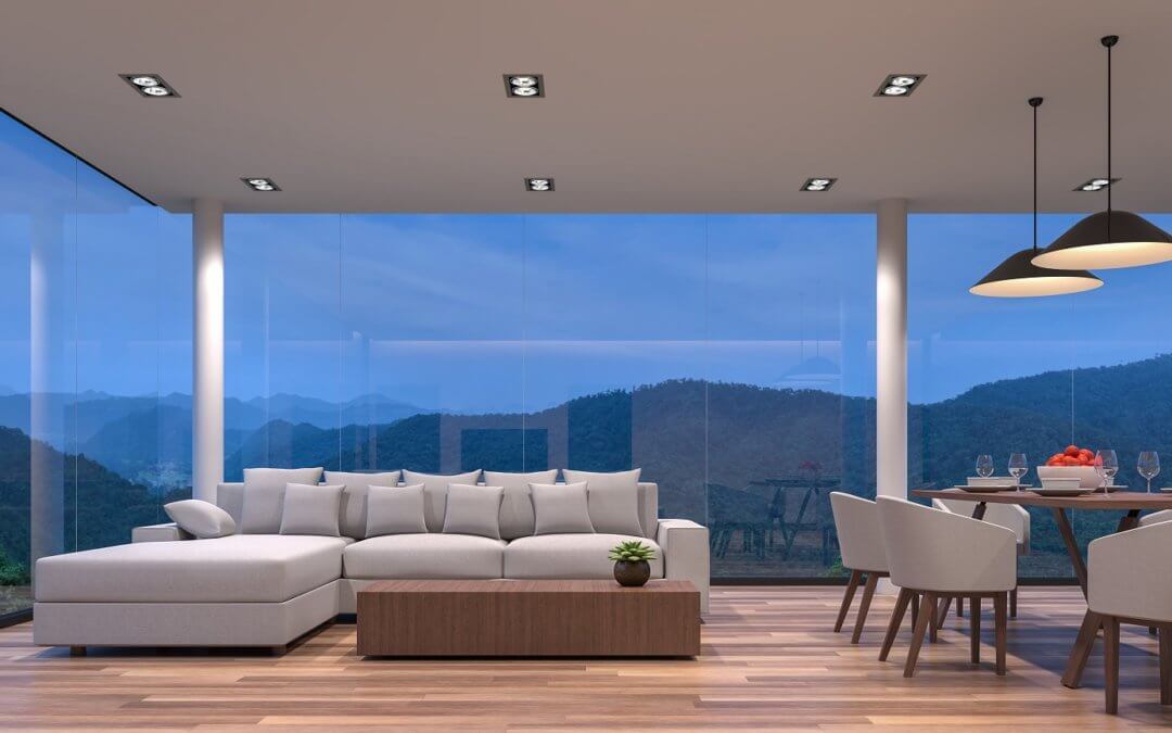 Night scene glass house living and dining room with mountain view 3d rendering image.The room has wooden floor,There are large frame less glass window overlooking to the mountain and nature